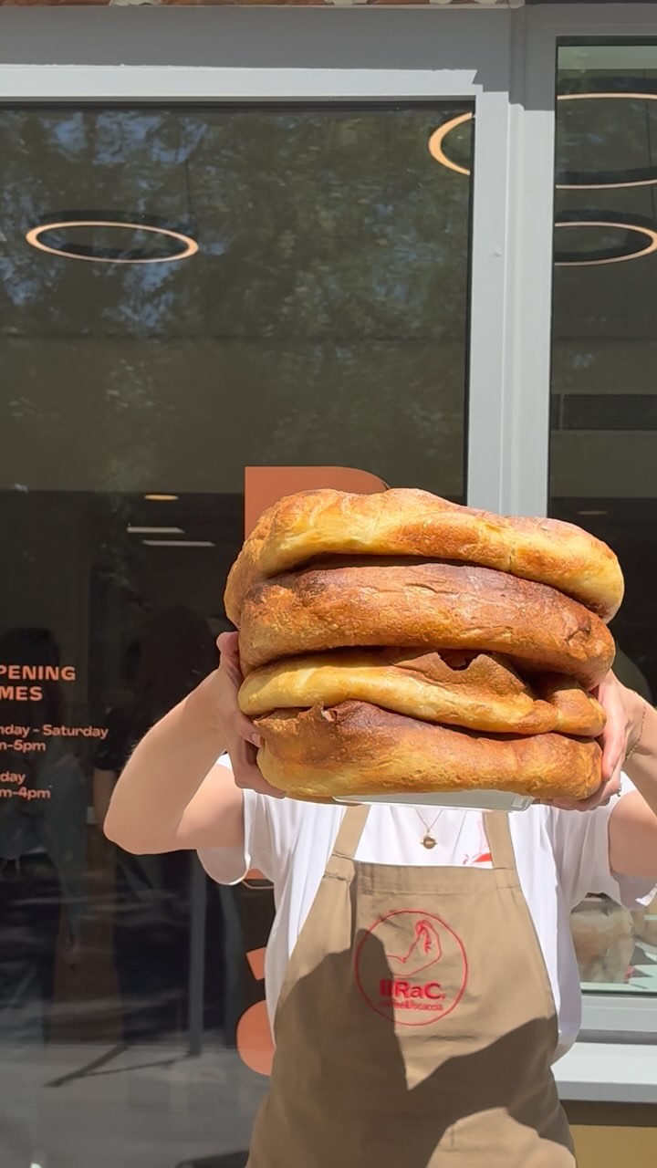 A BRaC. team member holding freshly baked focaccia outside the café