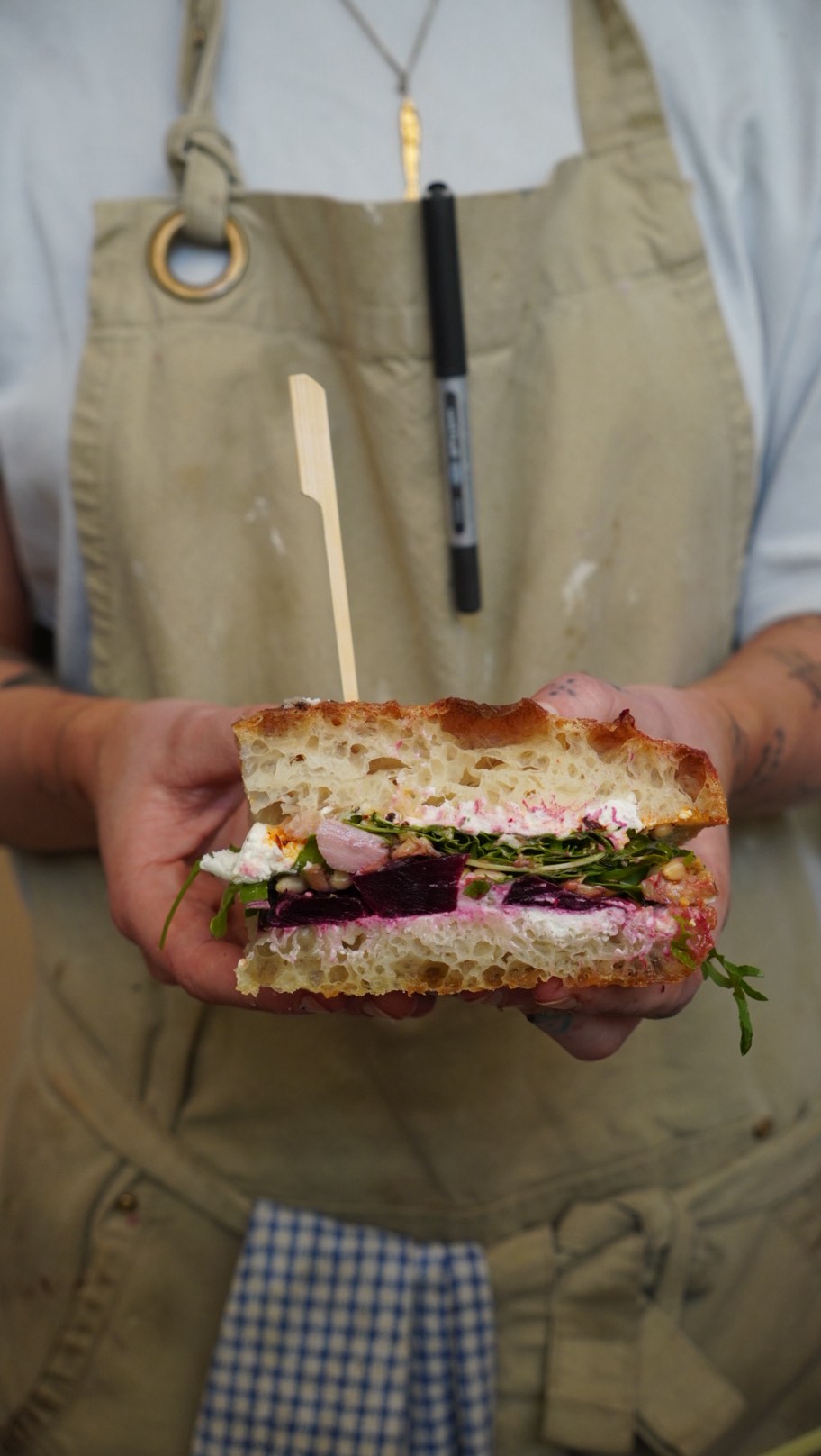 A colourful focaccia sandwich held by a BRaC. team member