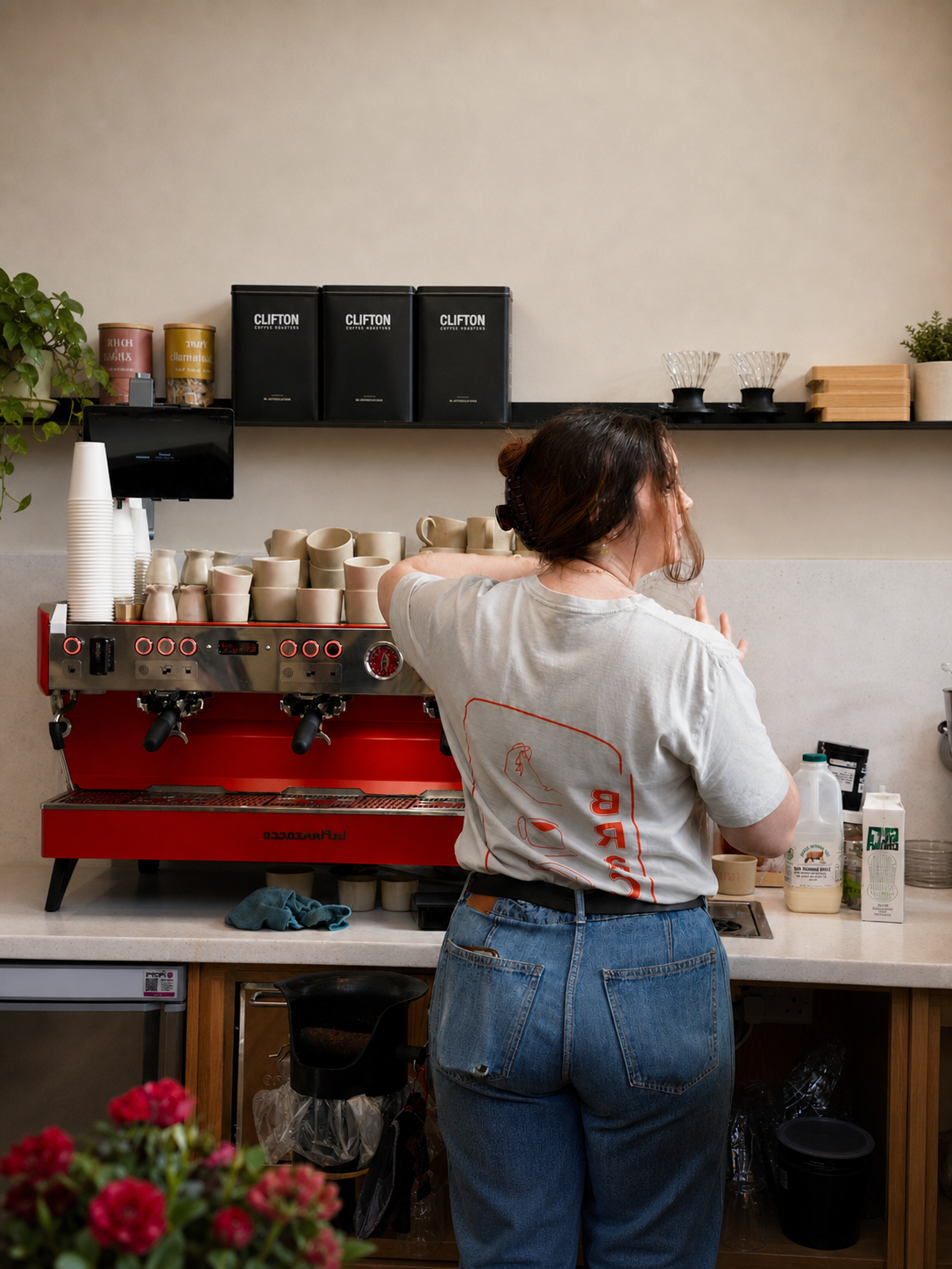 A BRaC. team member preparing coffee at a red espresso machine